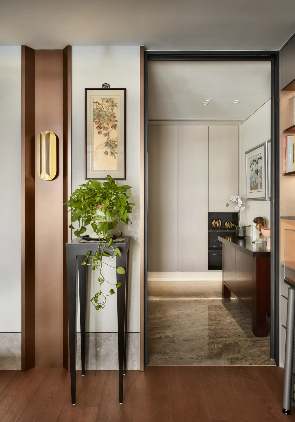 Entry passage — bronze-tone pilasters, traditional scroll painting, and pocket kitchen beyond