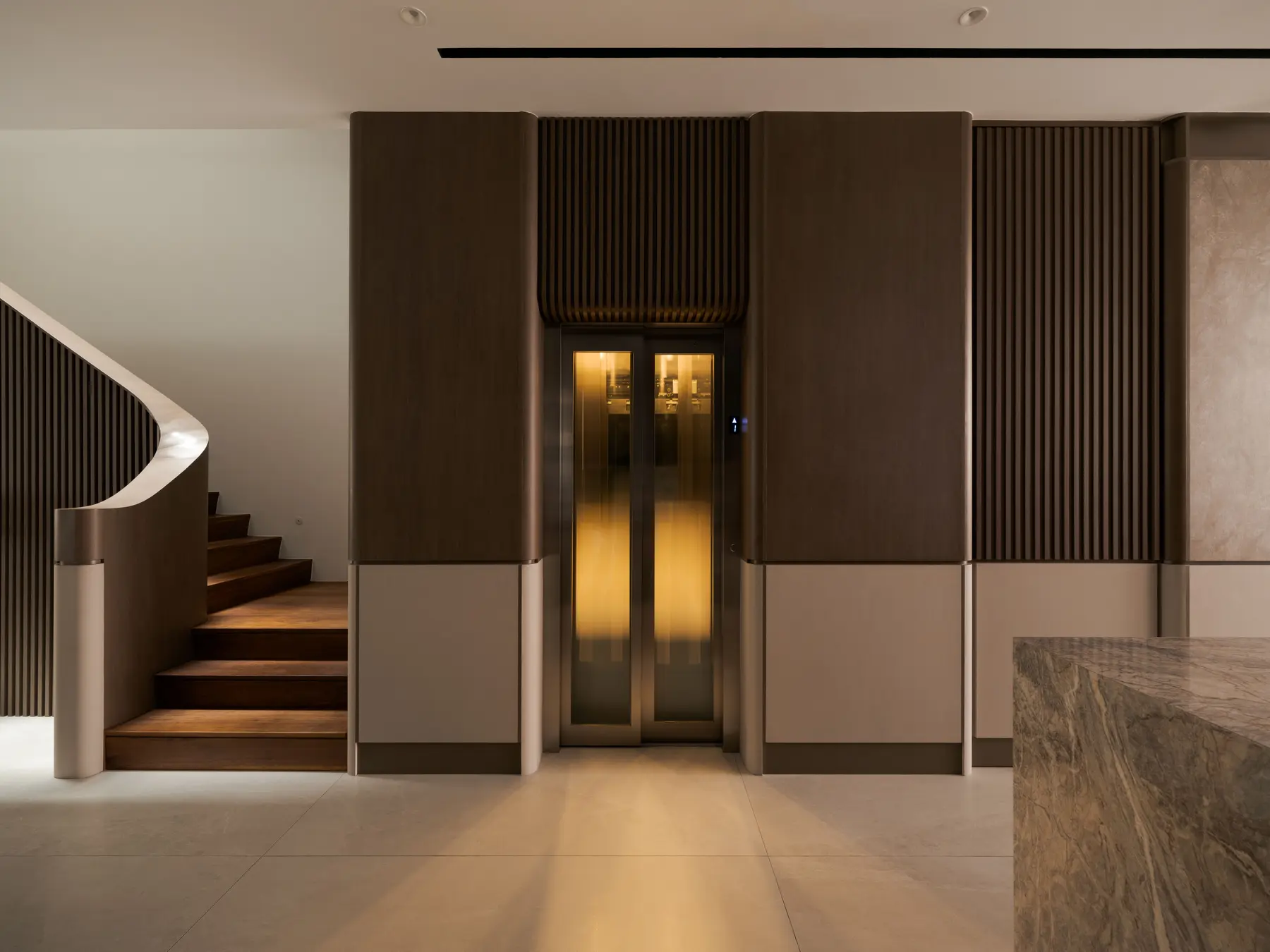 Staircase base and lift — dark timber slats, marble counter edge and curved stair